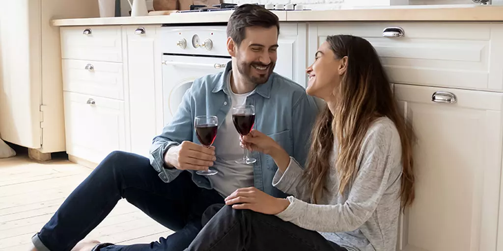 Ein Pärchen sitzt auf dem Küchenboden mit einem Glas Wein