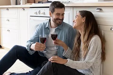 Ein Pärchen sitzt auf dem Küchenboden mit einem Glas Wein