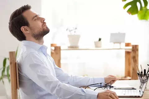 Mann versucht sich am Tisch zu entspannen