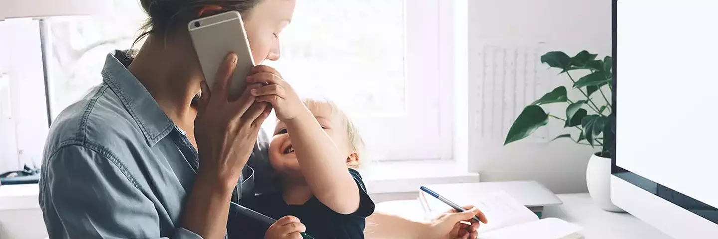 Frau am Arbeiten mit Telefon und Kind