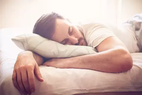 Mann liegt erschöpft auf dem Bett