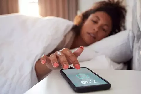 Frau stellt den Wecker auf ihrem Handy ein