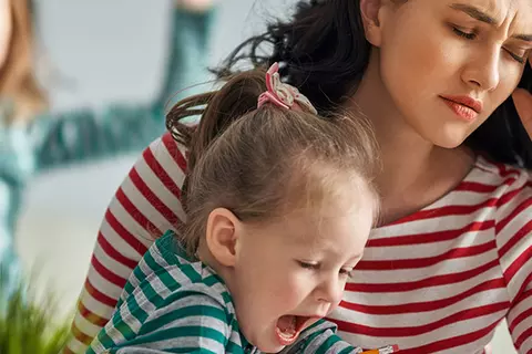 Gestresste Mutter am Laptop mit tobenden Kindern