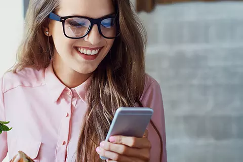 Lächelnde Frau schaut auf ihr Handy