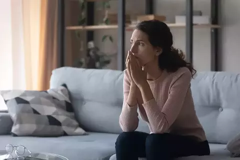 Frau sitzt auf dem Sofa und denkt nach