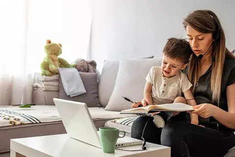 Frau mit Kind arbeitet auf dem Sofa
